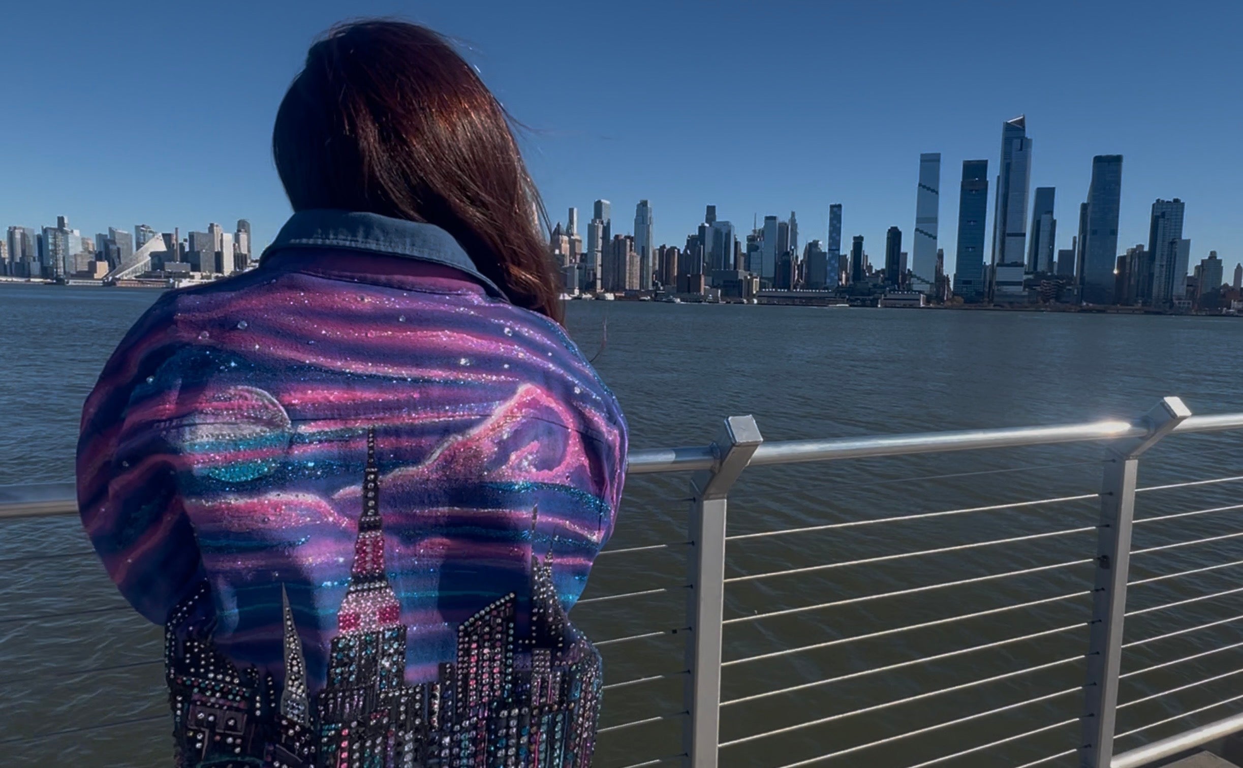 Person wearing a colorful Loria NYC Art jacket with city skyline reflection