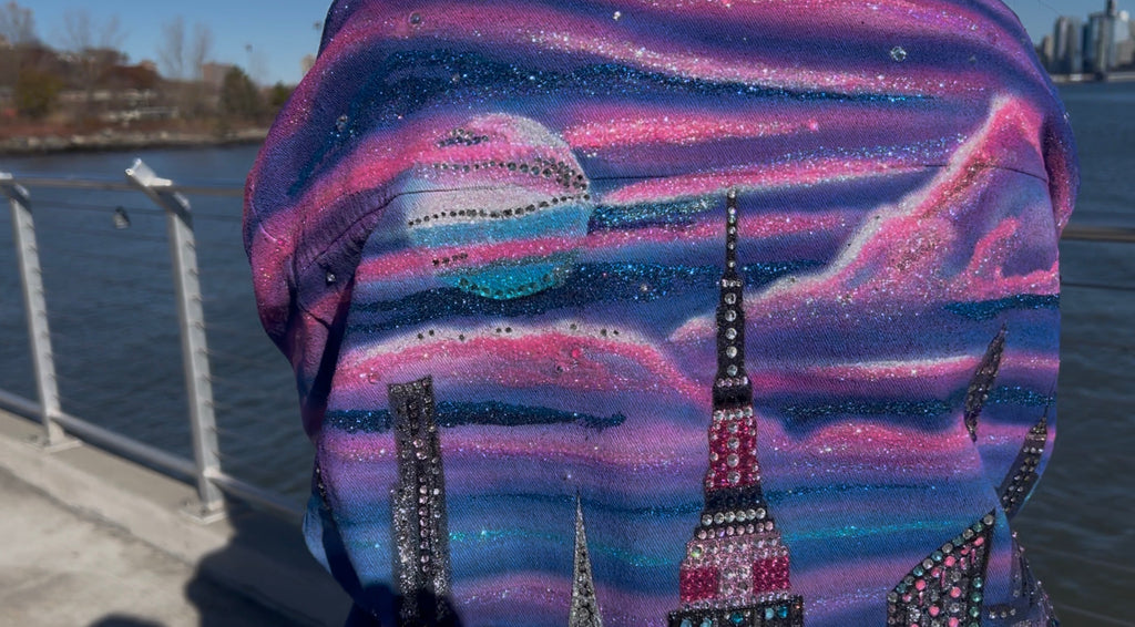 Backpack with a cityscape Loria NYC Art design featuring tall buildings, including the Empire State Building , against a blue sky. 