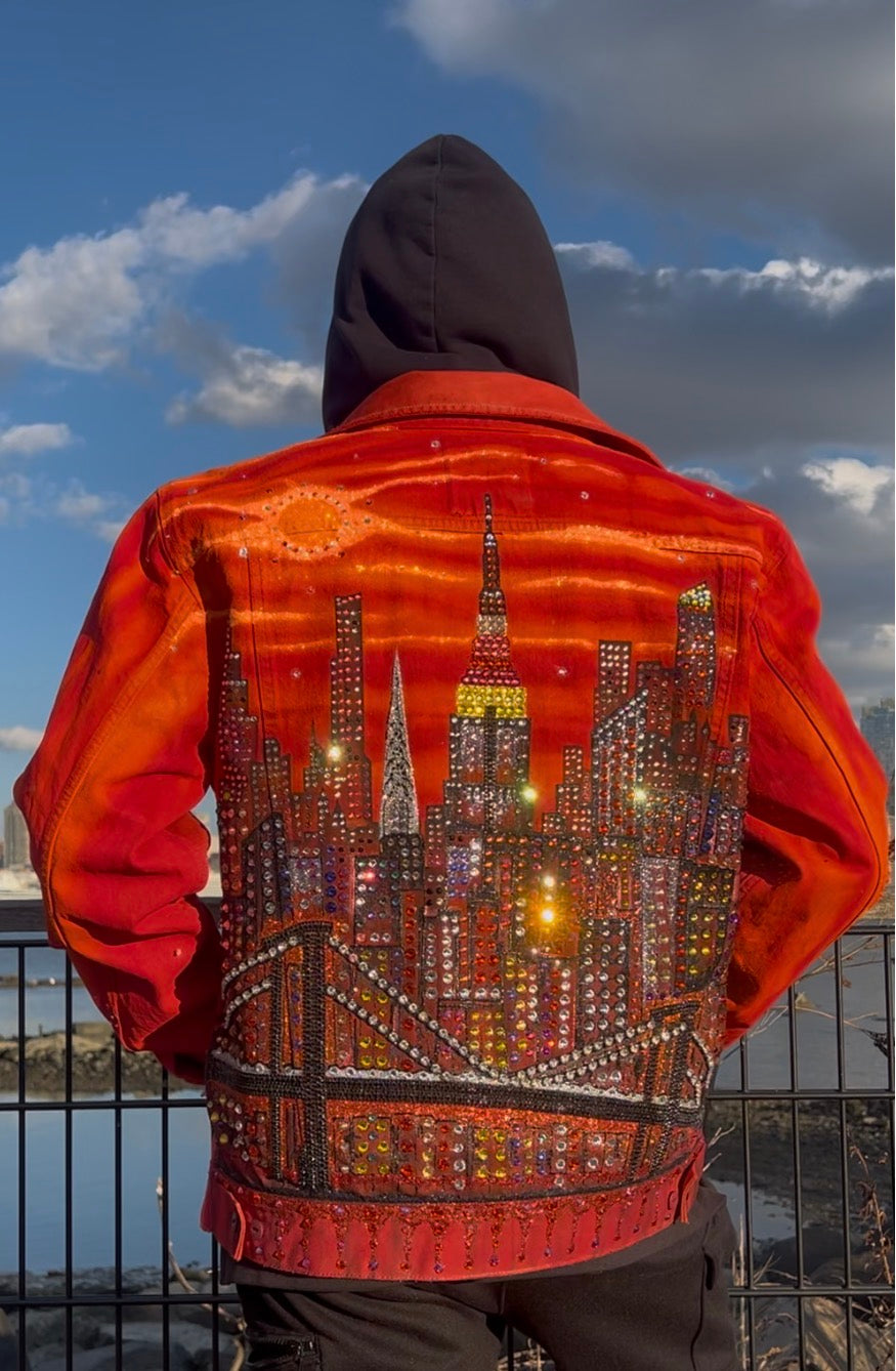 Person wearing a vibrant orange Loria NYC Art jacket outside with reflecting crystals.