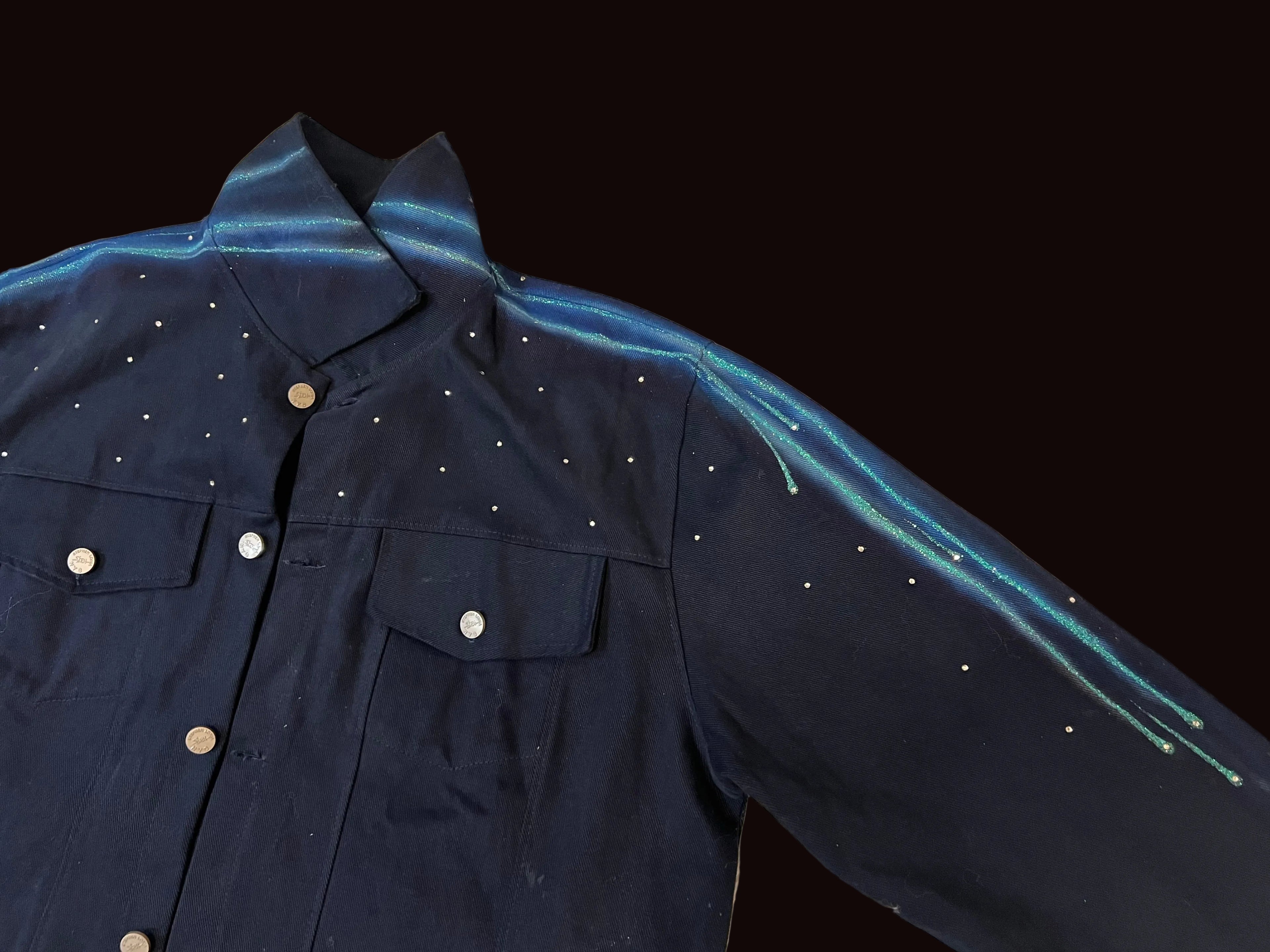 Navy blue jacket with white button details on a beige textured surface
