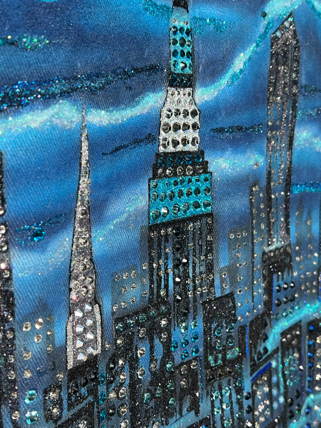 Close-up of a decorative fabric with blue and black Loria NYC Art on a blue background