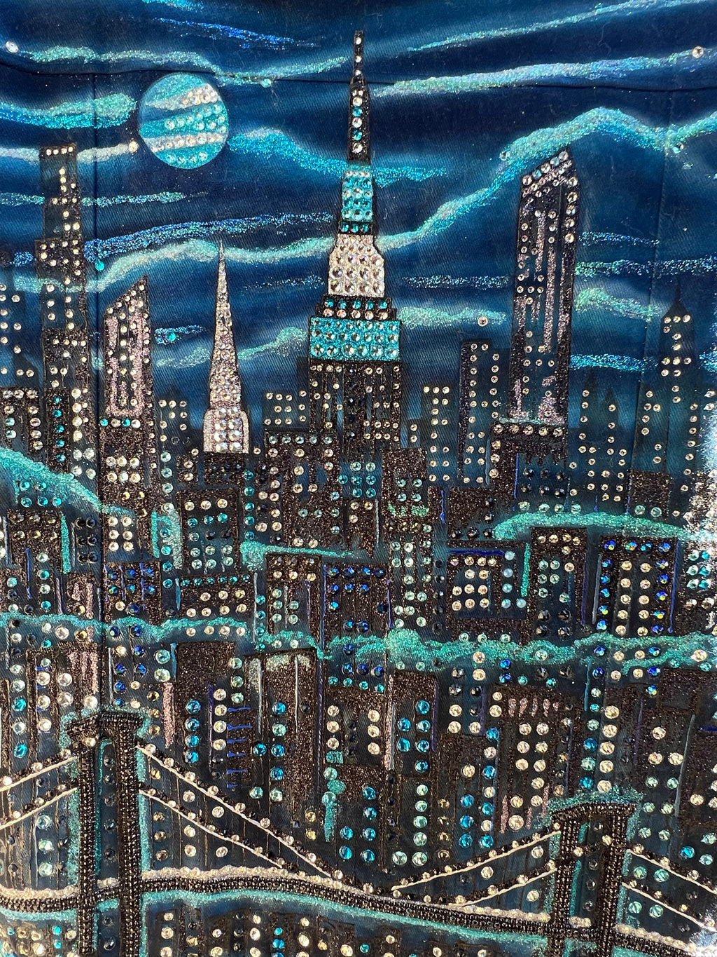 Close-up of a blue fabric with intricate Loria NYC Art beadwork and patterns