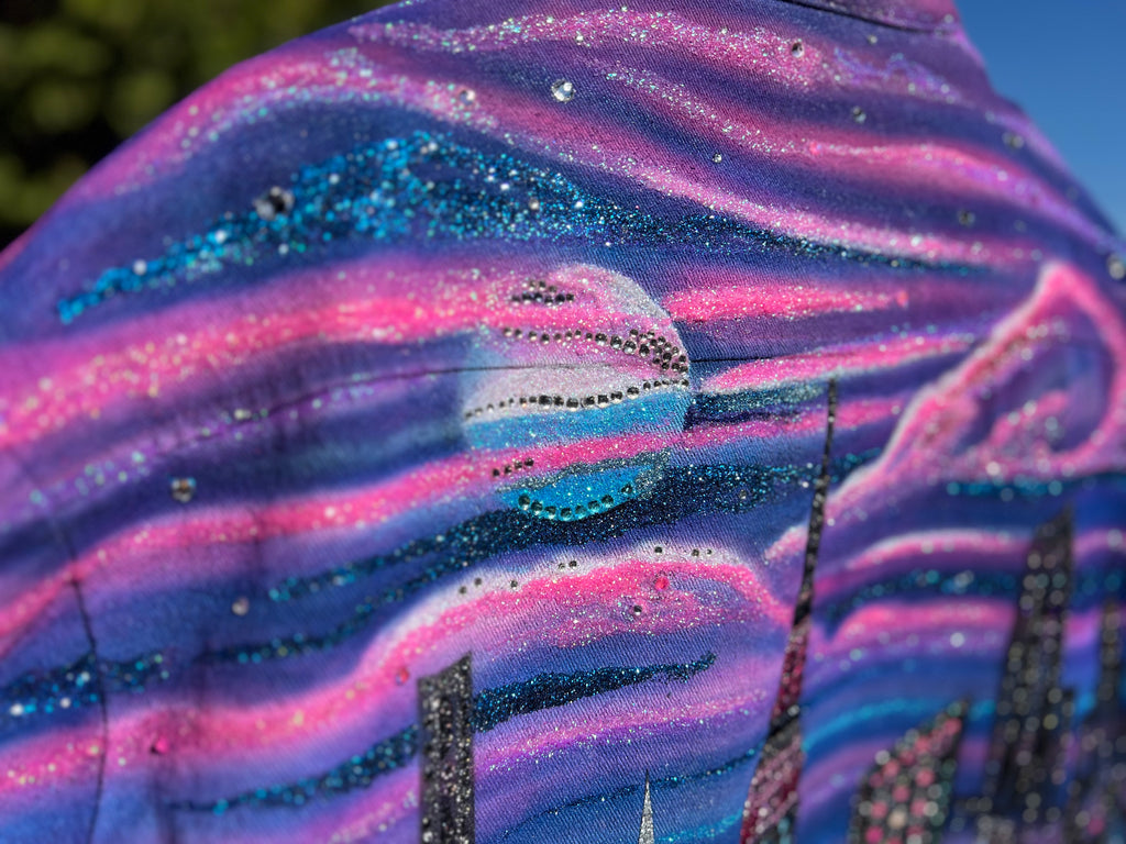 Close up view of a  reflective purple pink colorful Loria NYC Art jacket with the crystals on a moon design.