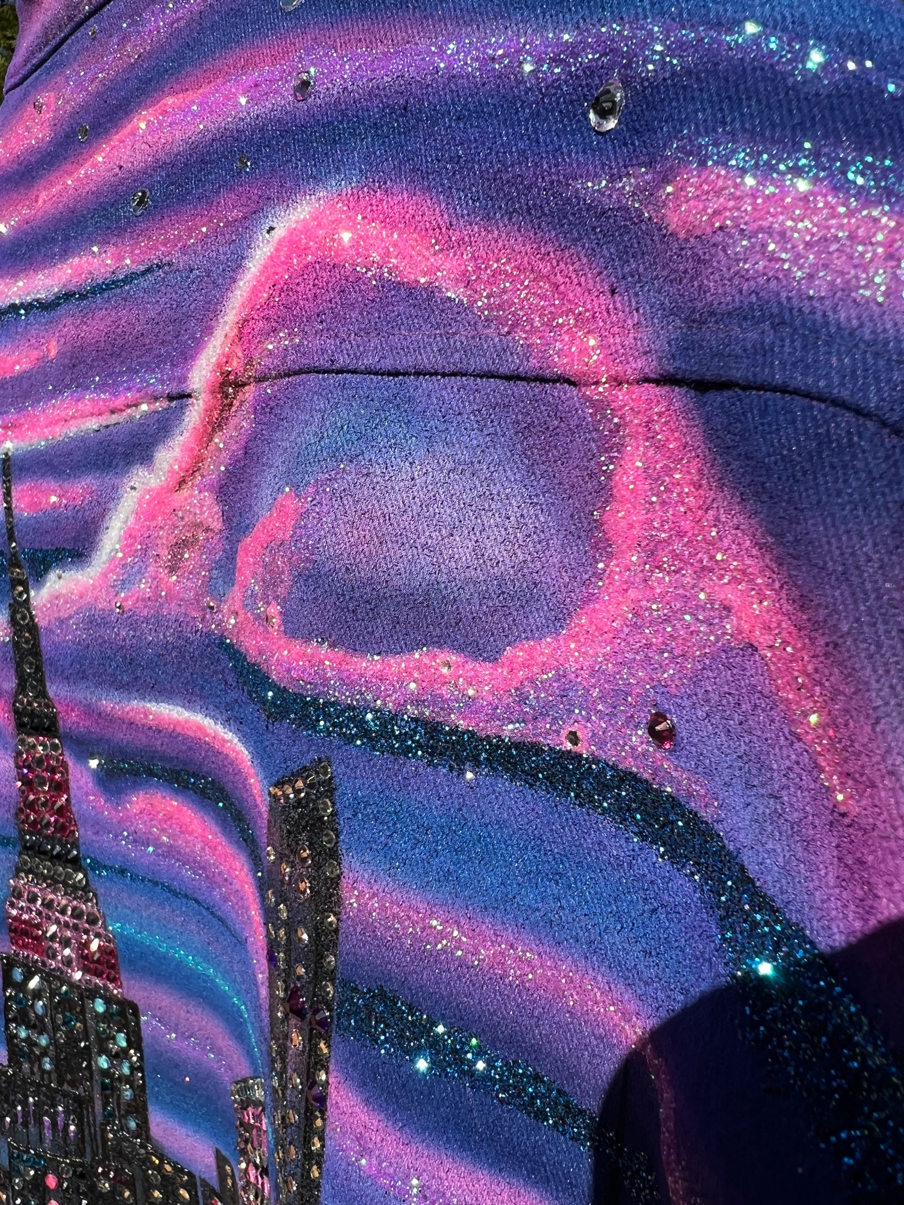 Close-up of a Loria NYC Art glittery fabric with pink and purple swirls and sequins.