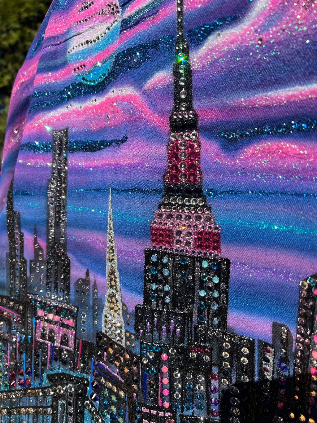 Close-up of a Loria NYC Art decorative jacket with rhinestones on a colorful fabric background