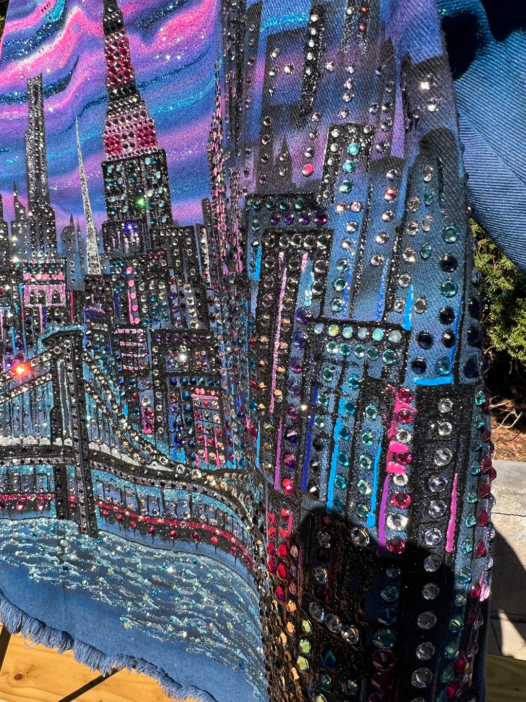 Close-up of a colorful, beaded design on a garment with a blue background.