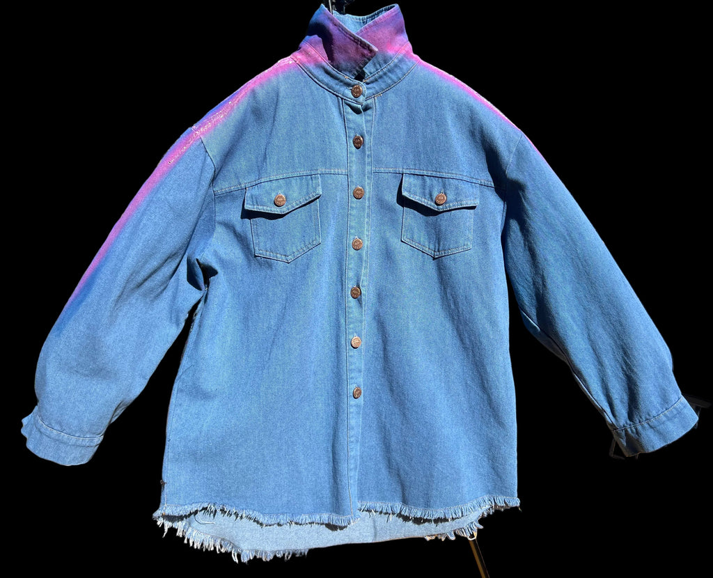 Blue denim Loria NYC Art jacket on a hanger with a blurred outdoor background