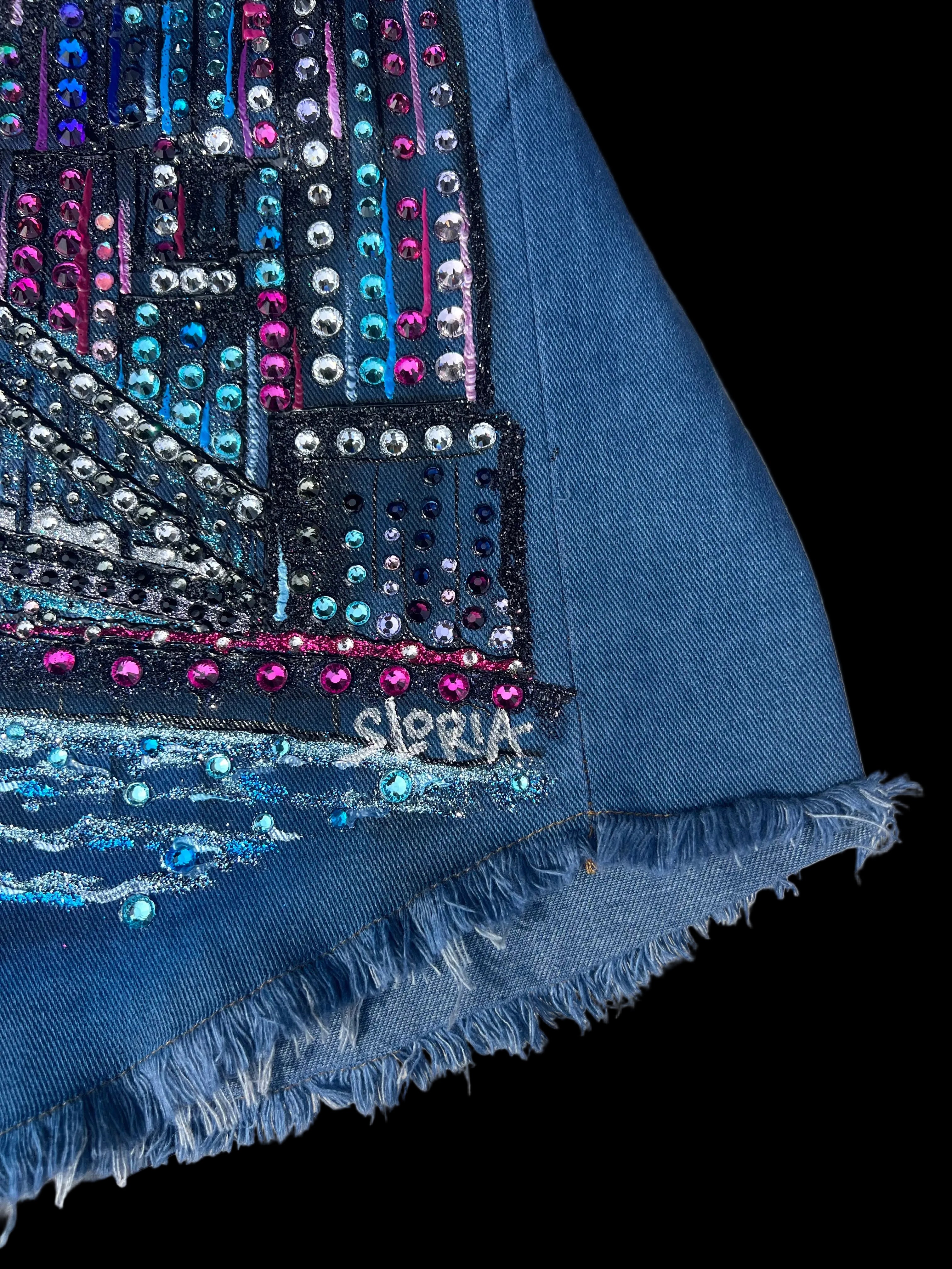 Blue fabric with embellishments and 'Sloria' branding on a wooden surface