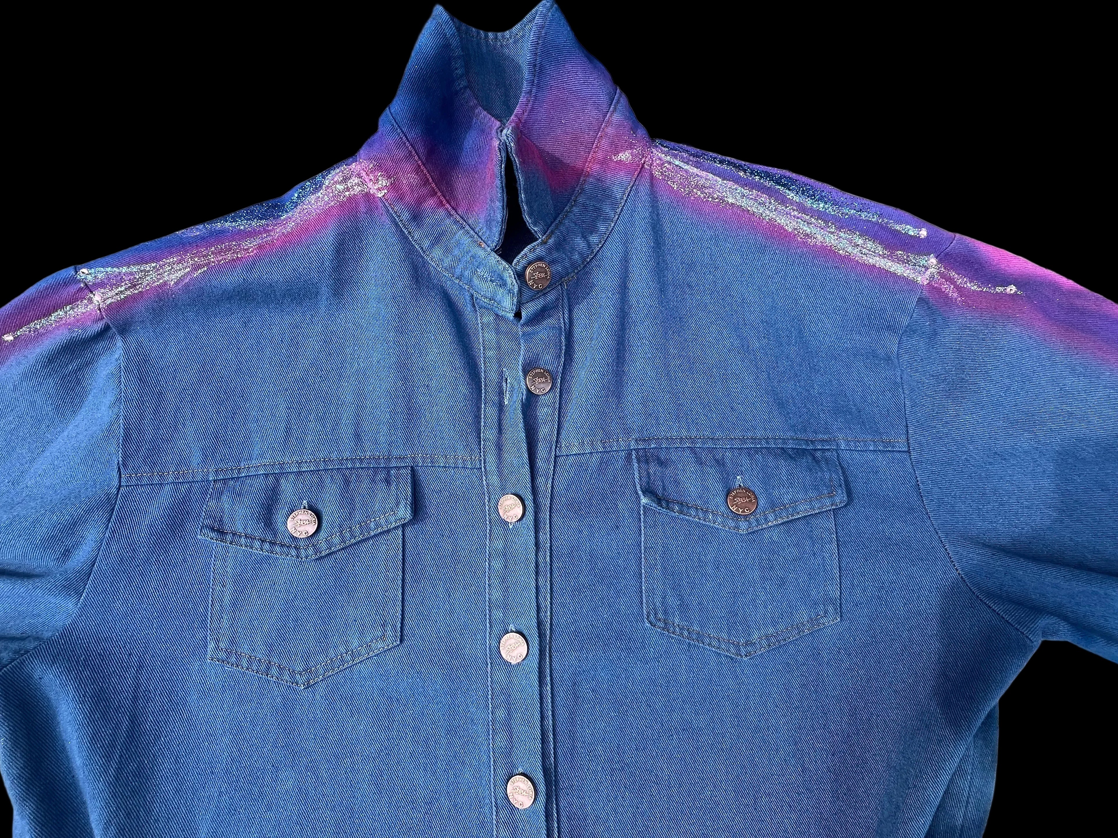 Blue denim shirt with a colorful Loria NYC Art on a textured surface