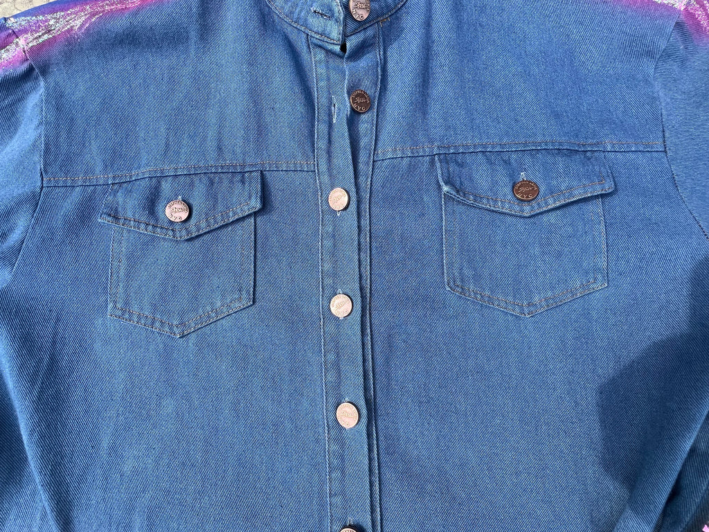 Blue denim shirt with Loria NYC Art button details on a plain background