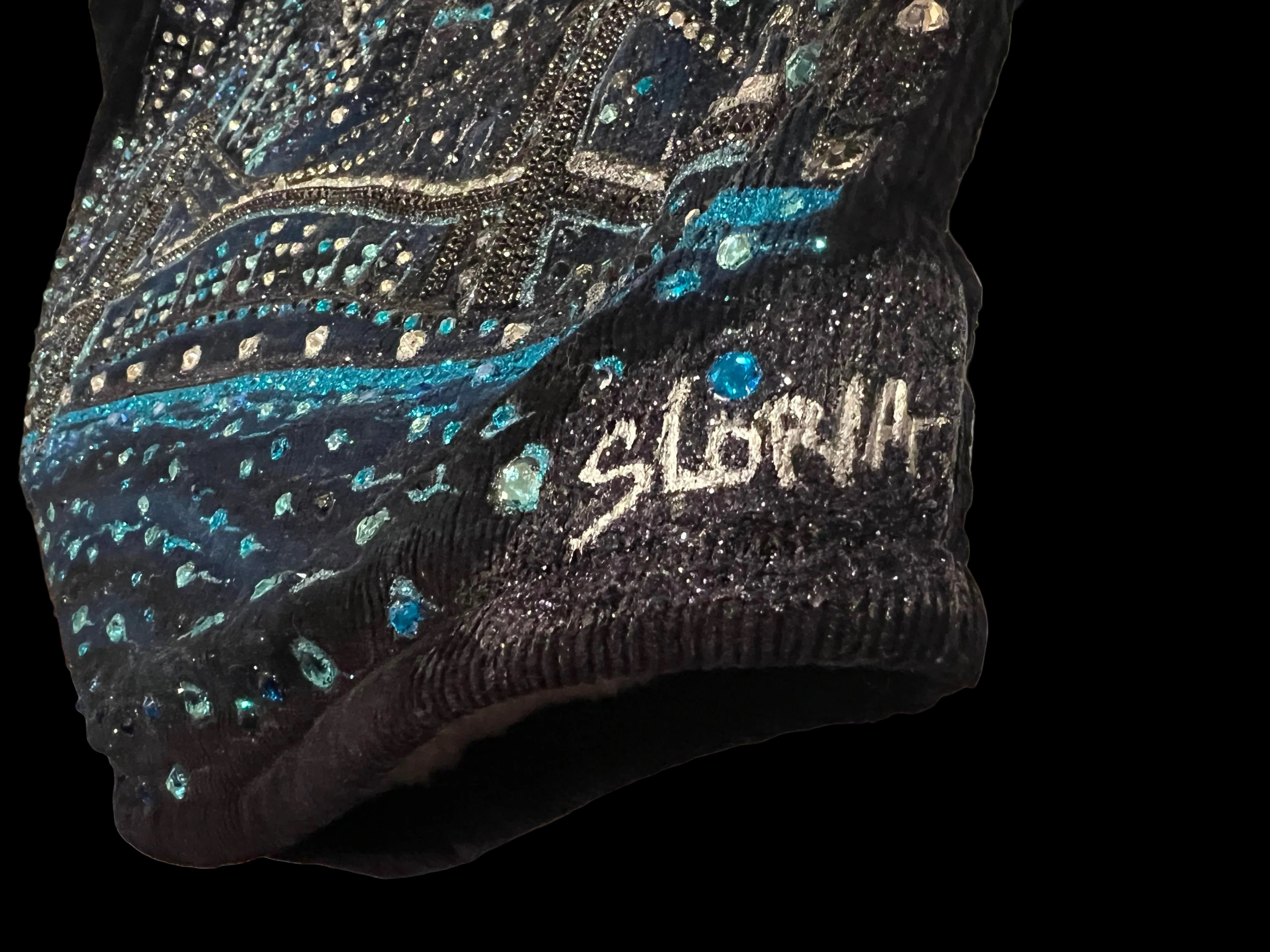 Black beaded Loria NYC Art garment with 'SLoria ' branding on a white surface