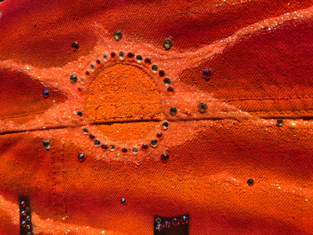 Close-up of a Loria NYC Art orange fabric surface with circular patterns and small embellishments.