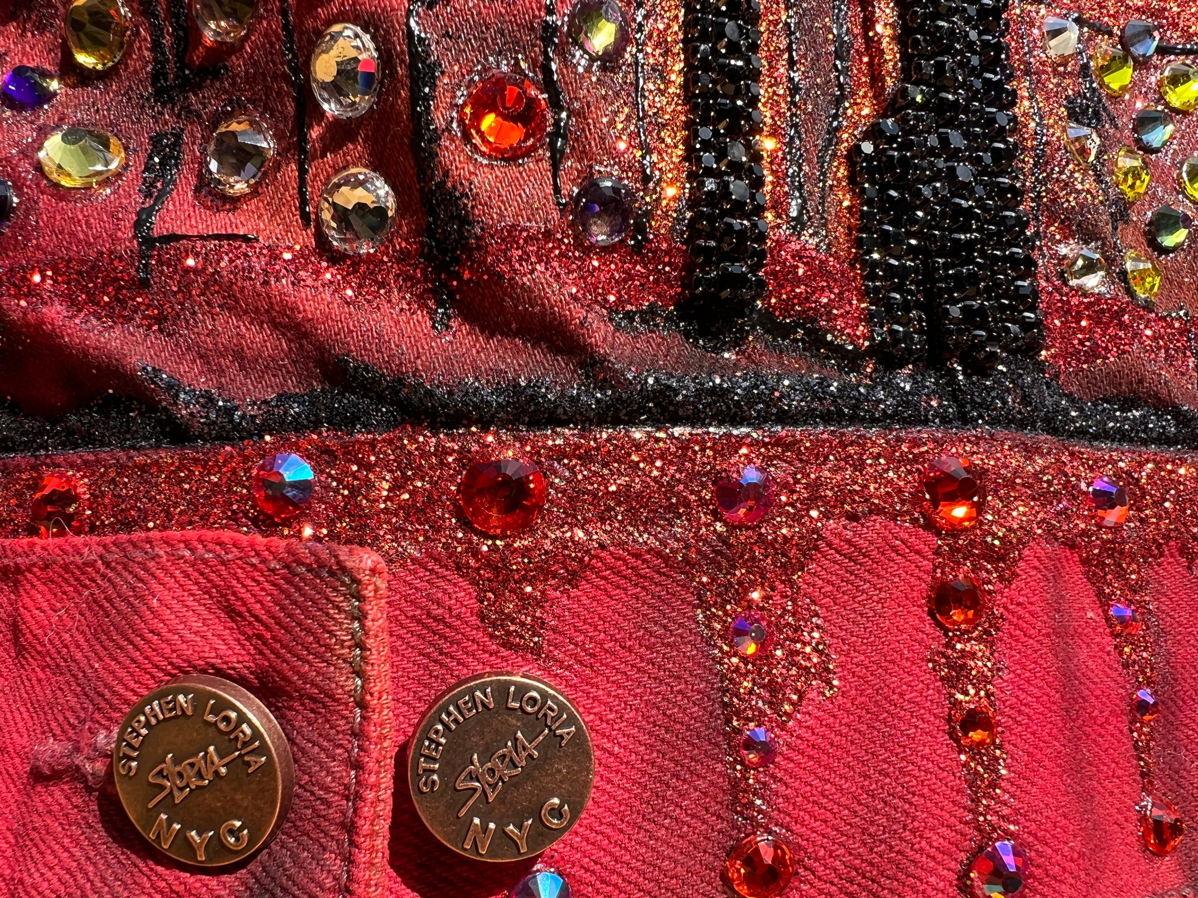 Close-up of a red handbag with decorative elements and 'Stephen Loria' branding.