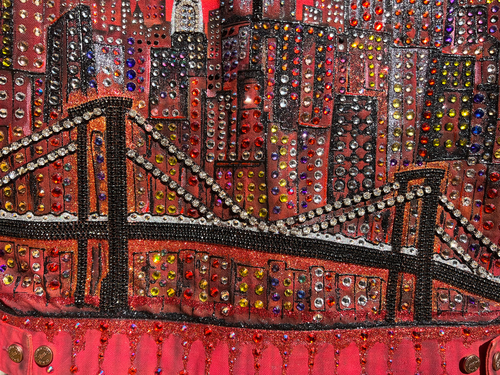 Close-up of a beaded or embroidered fabric with a Loria NYC Art cityscape design.