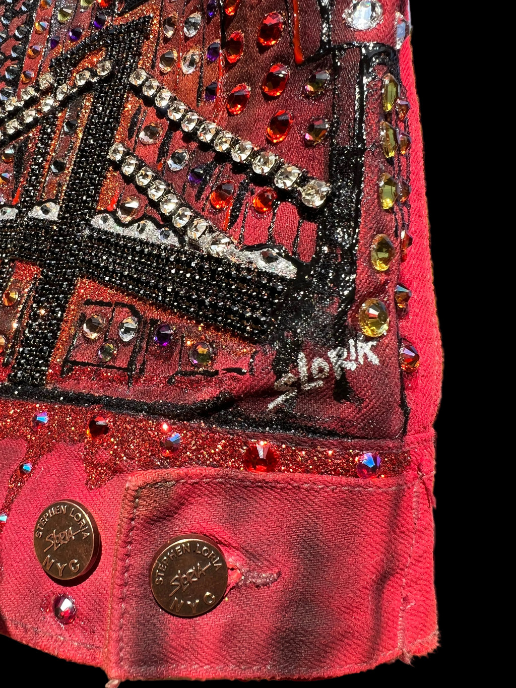 Close-up of a red jacket by Loria NYC Art  with decorative elements and crystals.