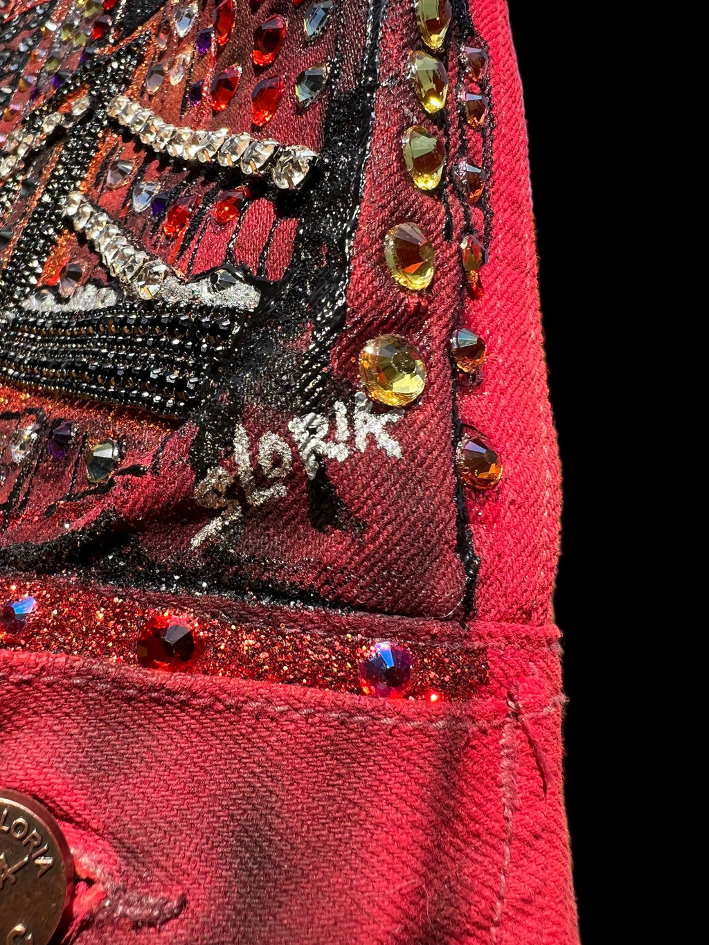 Close-up of a red fabric with Loria NYC Art decorative patterns and embellishments.