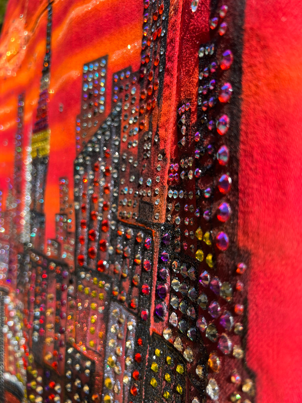 Close-up of a red fabric with colorful rhinestone Loria NYC Art patterns