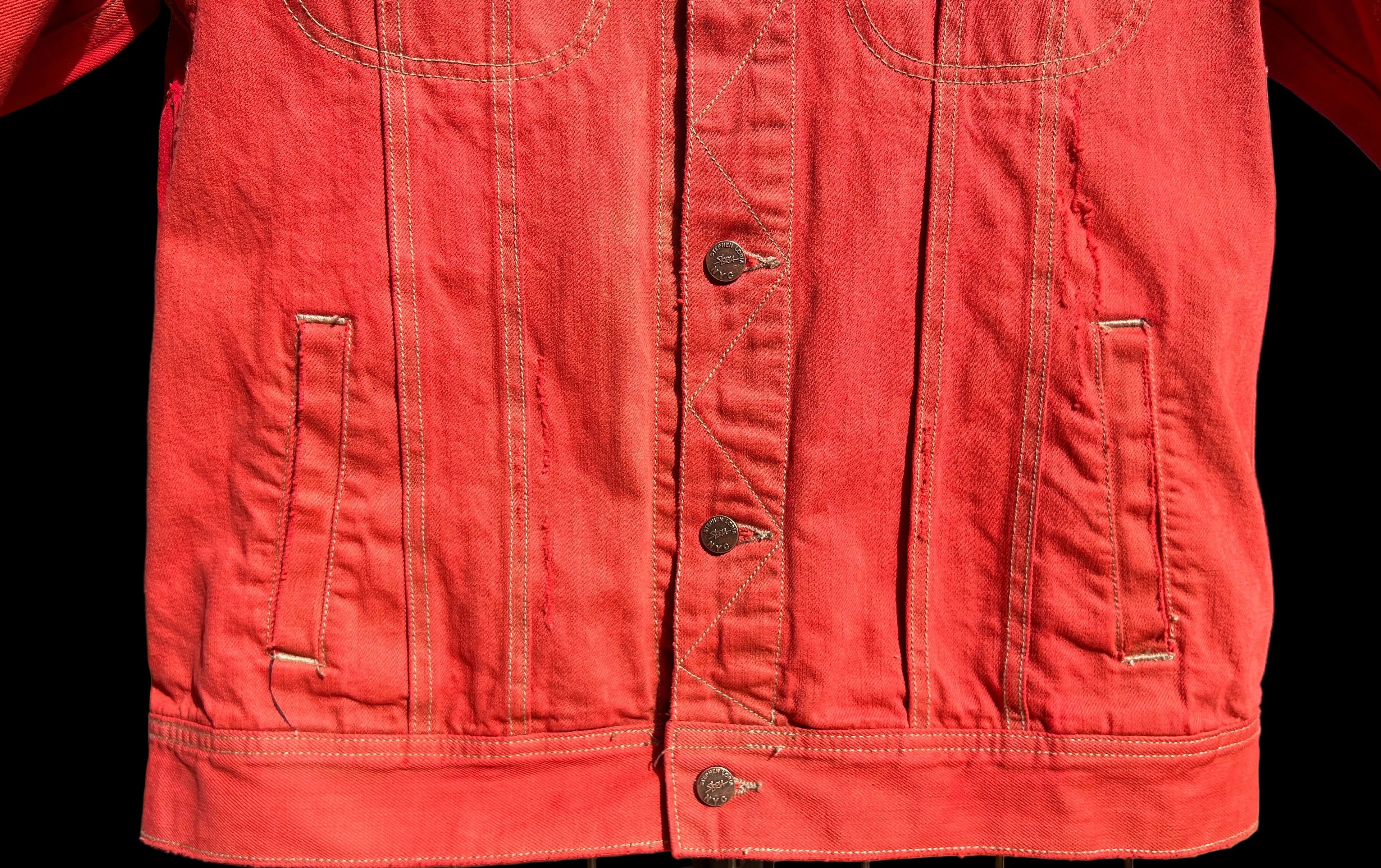 Red jacket on a rack outdoors with a Loria NYC Art background