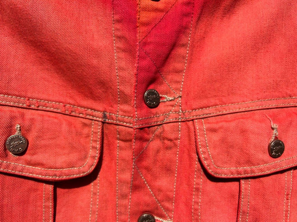 Close-up of a red denim jacket with Loria NYC Art button details