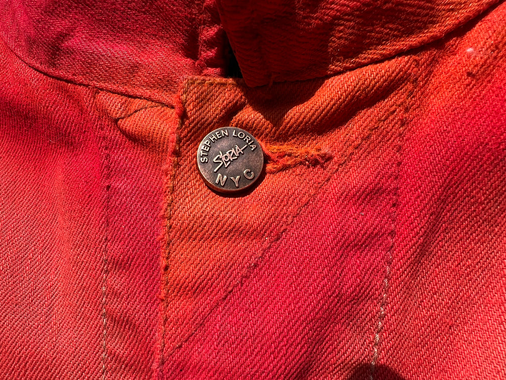 Close-up of a red jacket with a button featuring 'Stephen Loria' branding.