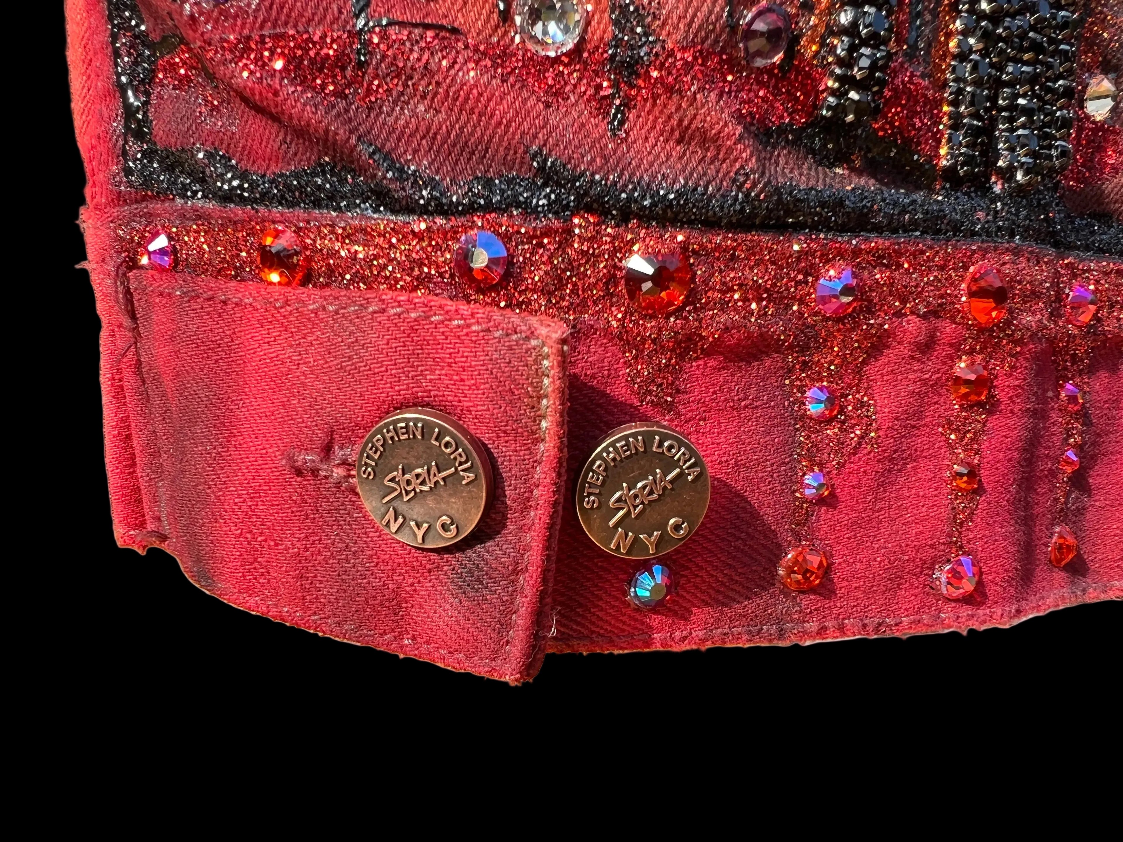Close-up of a red embellished jacket with 'Stephen Loria' branding on a black background 