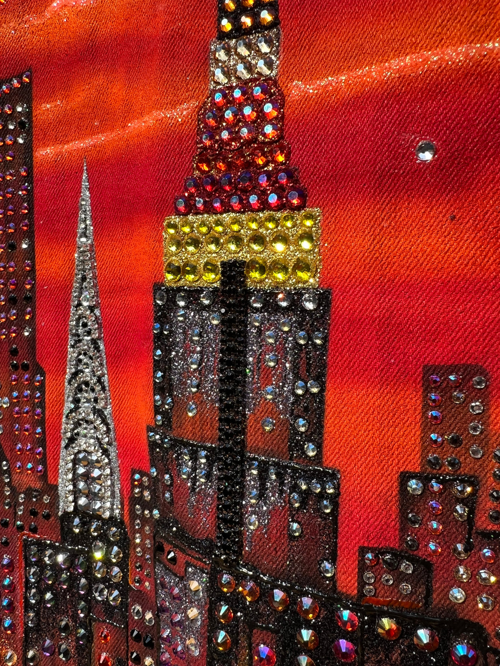 Close-up of a decorative  Loria NYC Art  fabric with rhinestones on a red background
