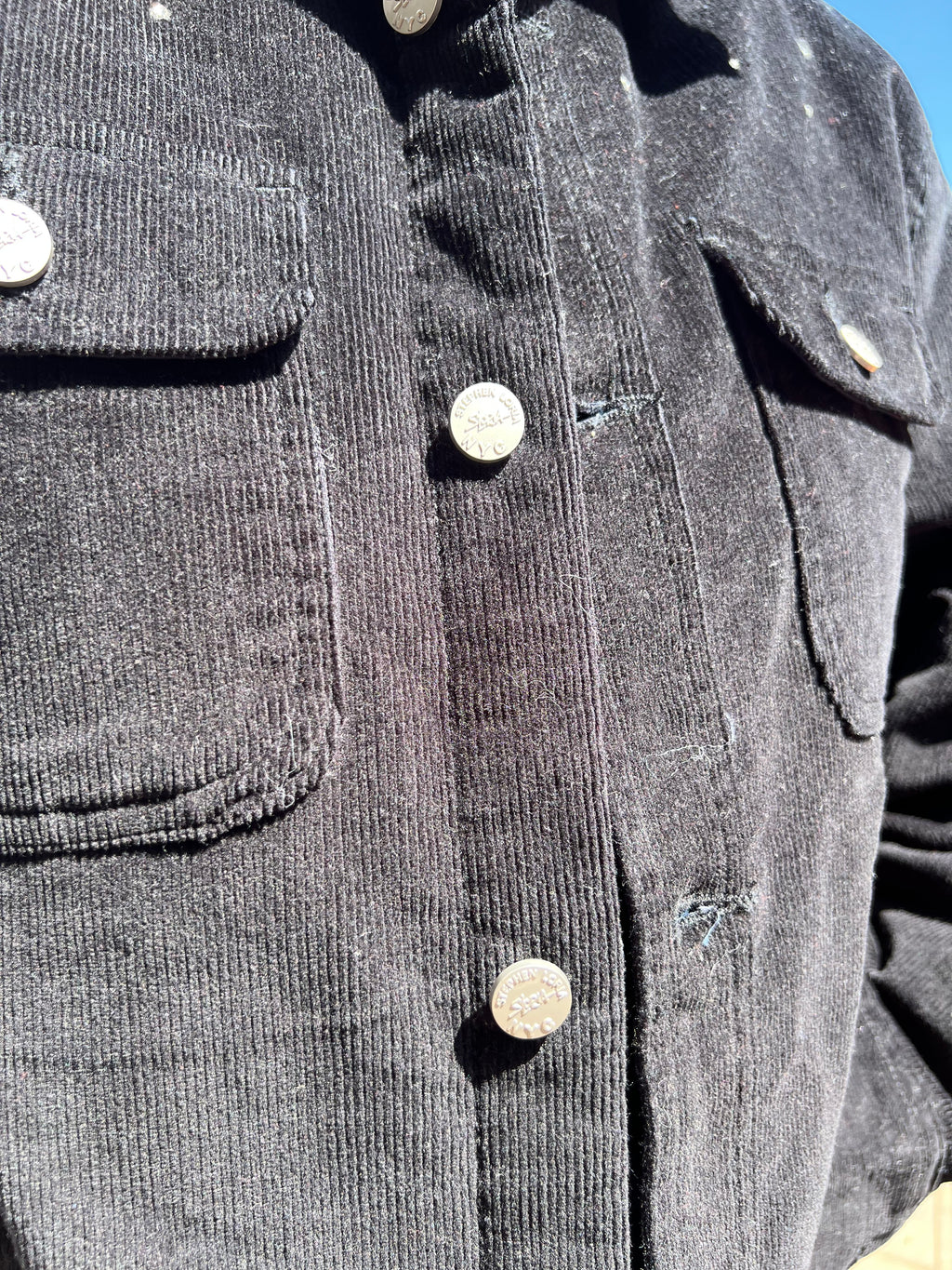 Close-up of a gray Loria NYC Art corduroy jacket with buttons and pockets.