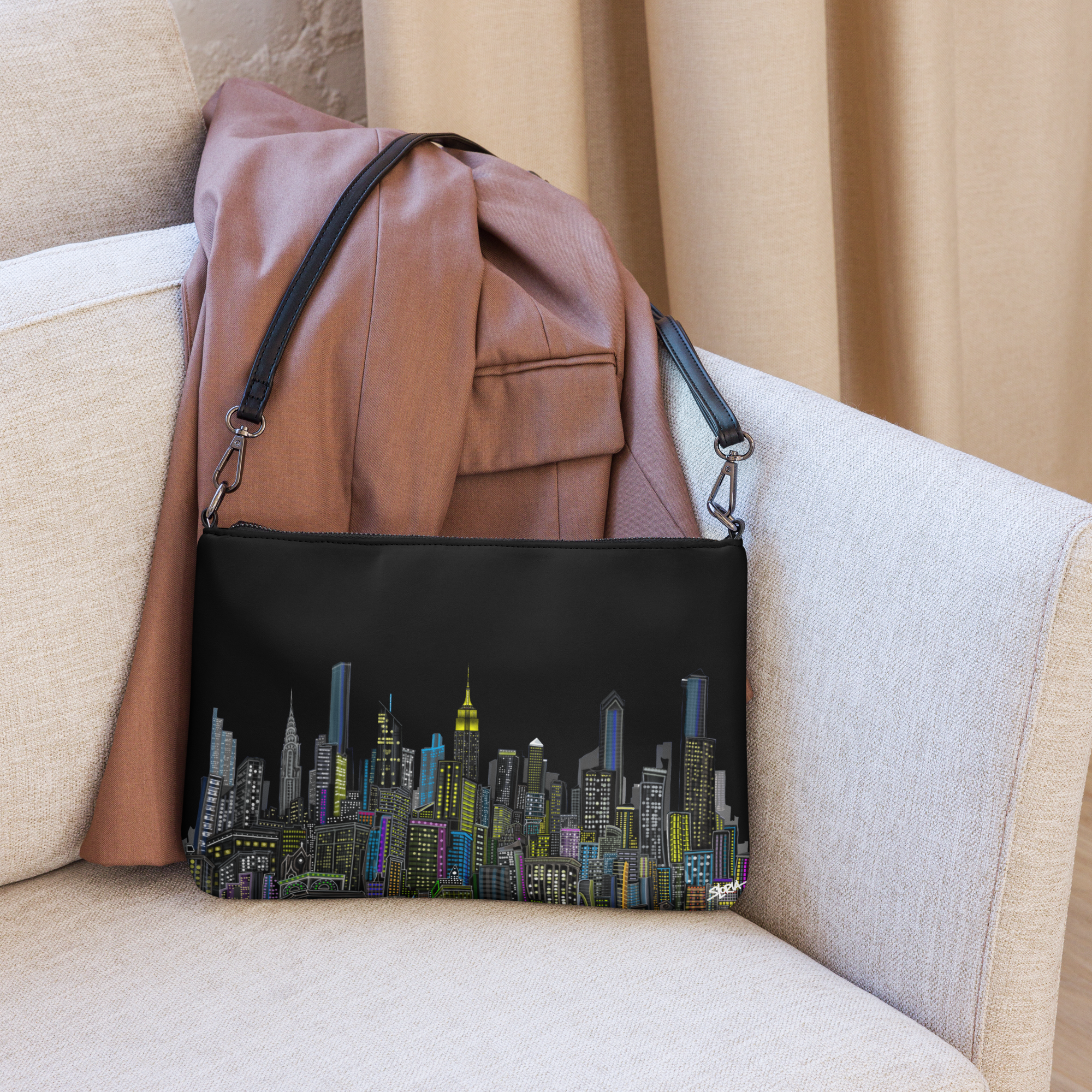 Black clutch with Loria NYC Art cityscape design on a beige couch