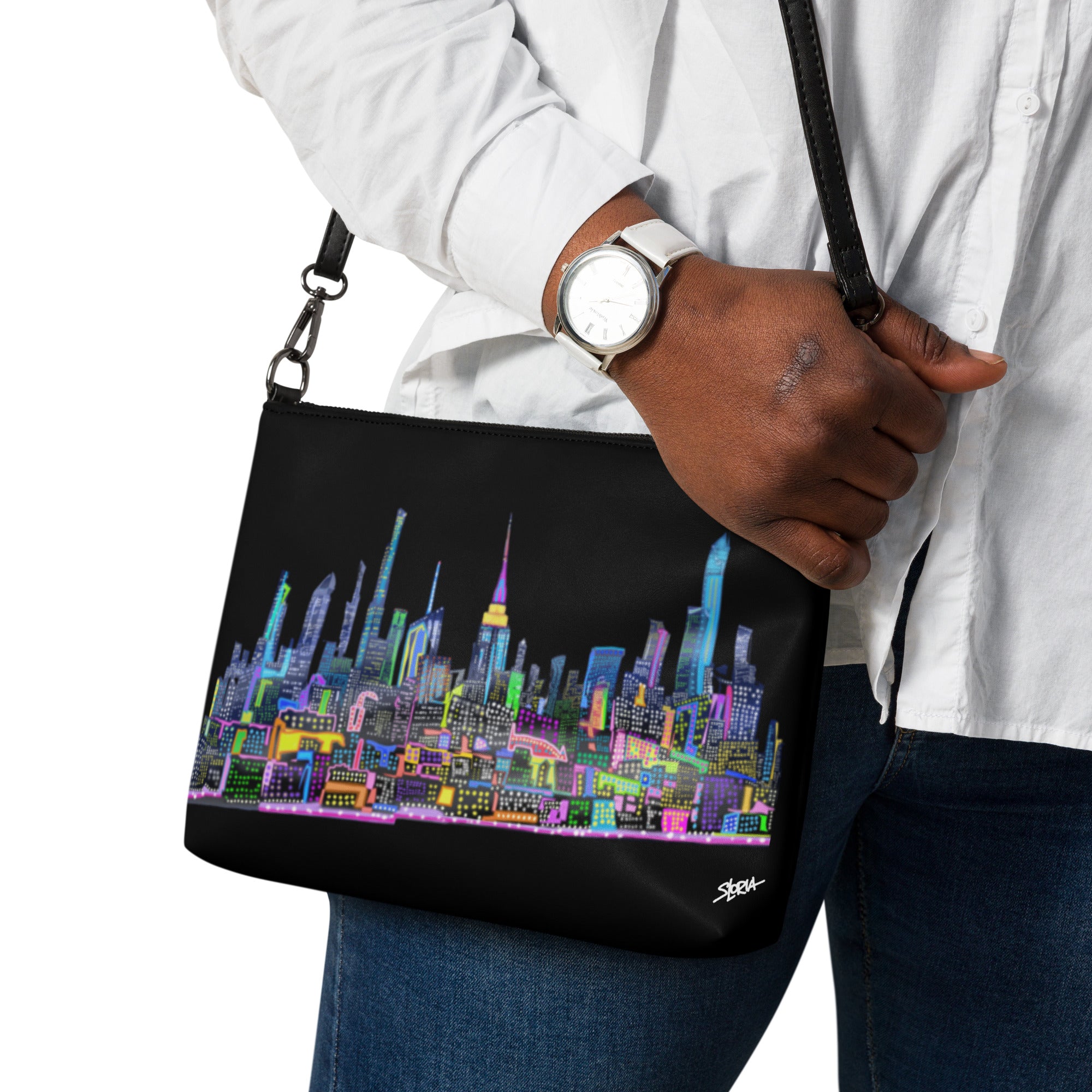 Person holding a black bag with a colorful cityscape design on a white background