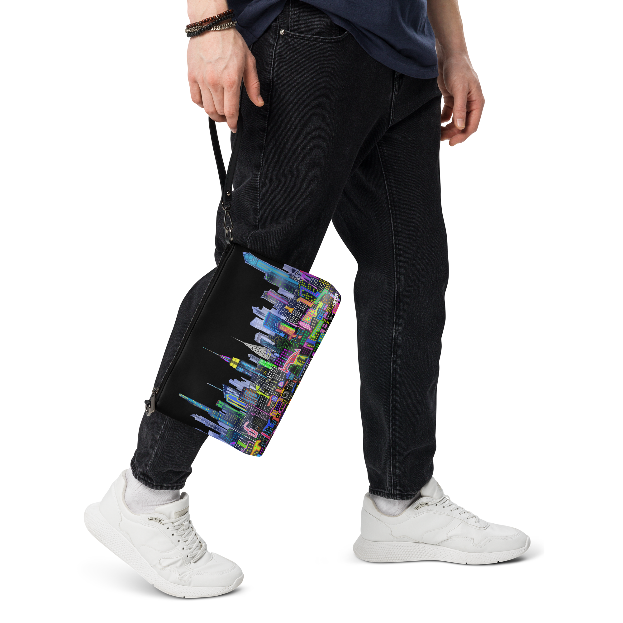 Person holding a colorful bag with a cityscape Loria NYC Art design, wearing black pants and white sneakers on a transparent background.