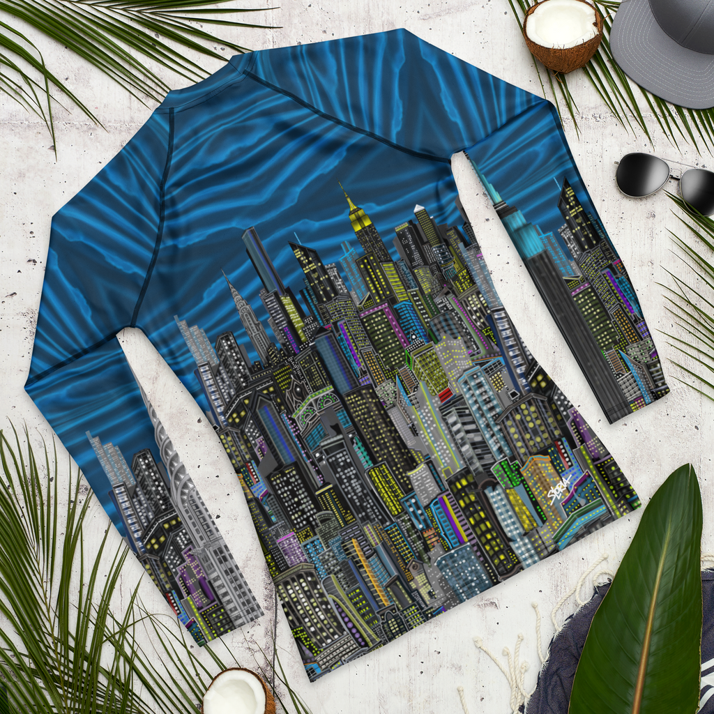 Long-sleeve shirt with cityscape Loria NYC Art design on a textured surface with leaves and a hat.