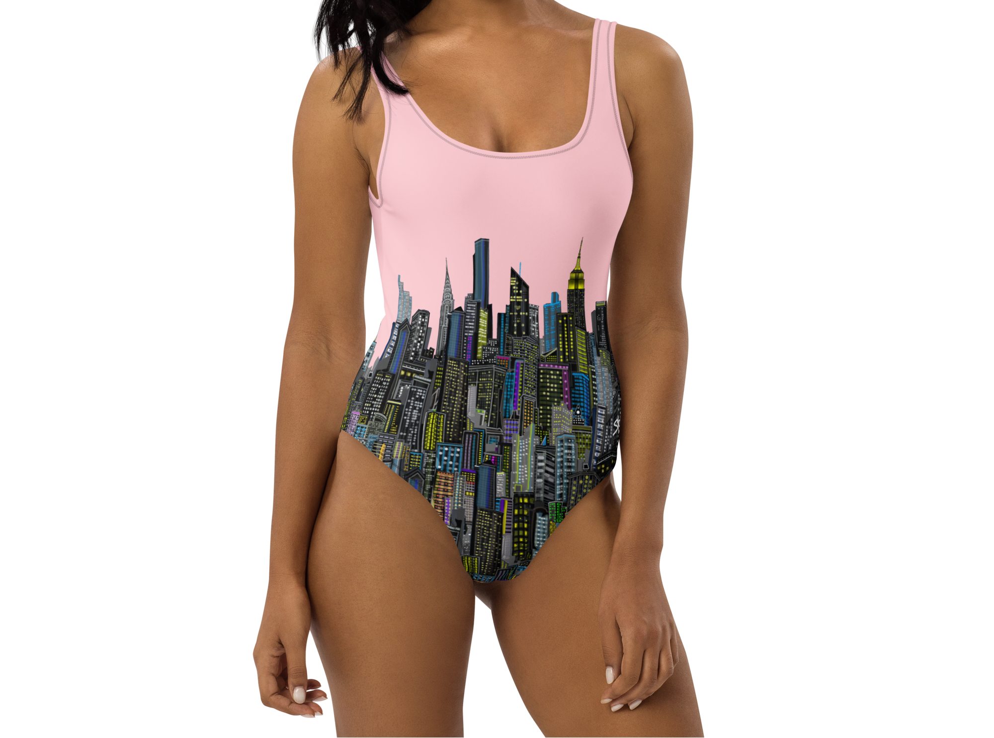 Woman wearing a pink Loria NYC Art one-piece swimsuit with cityscape design on a white background