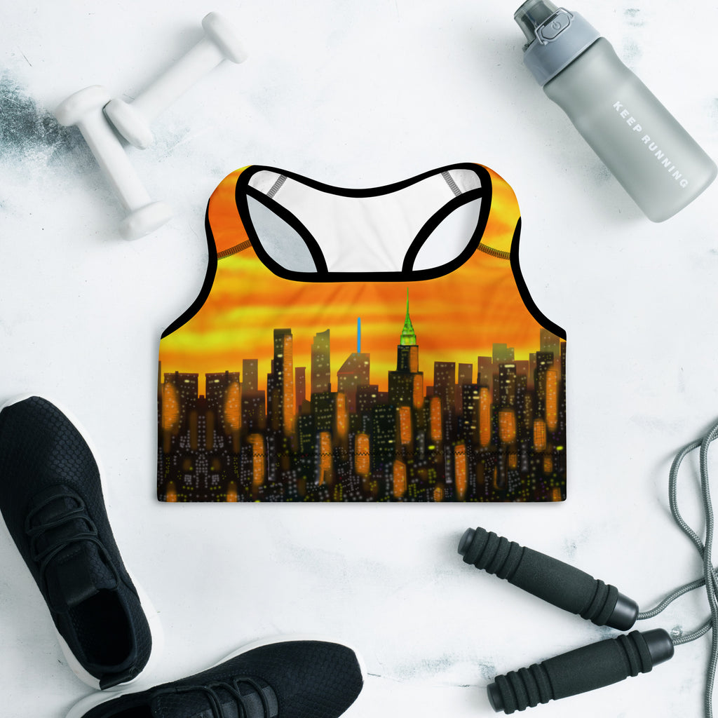 Sports bra with cityscape design on a white surface with gym equipment.