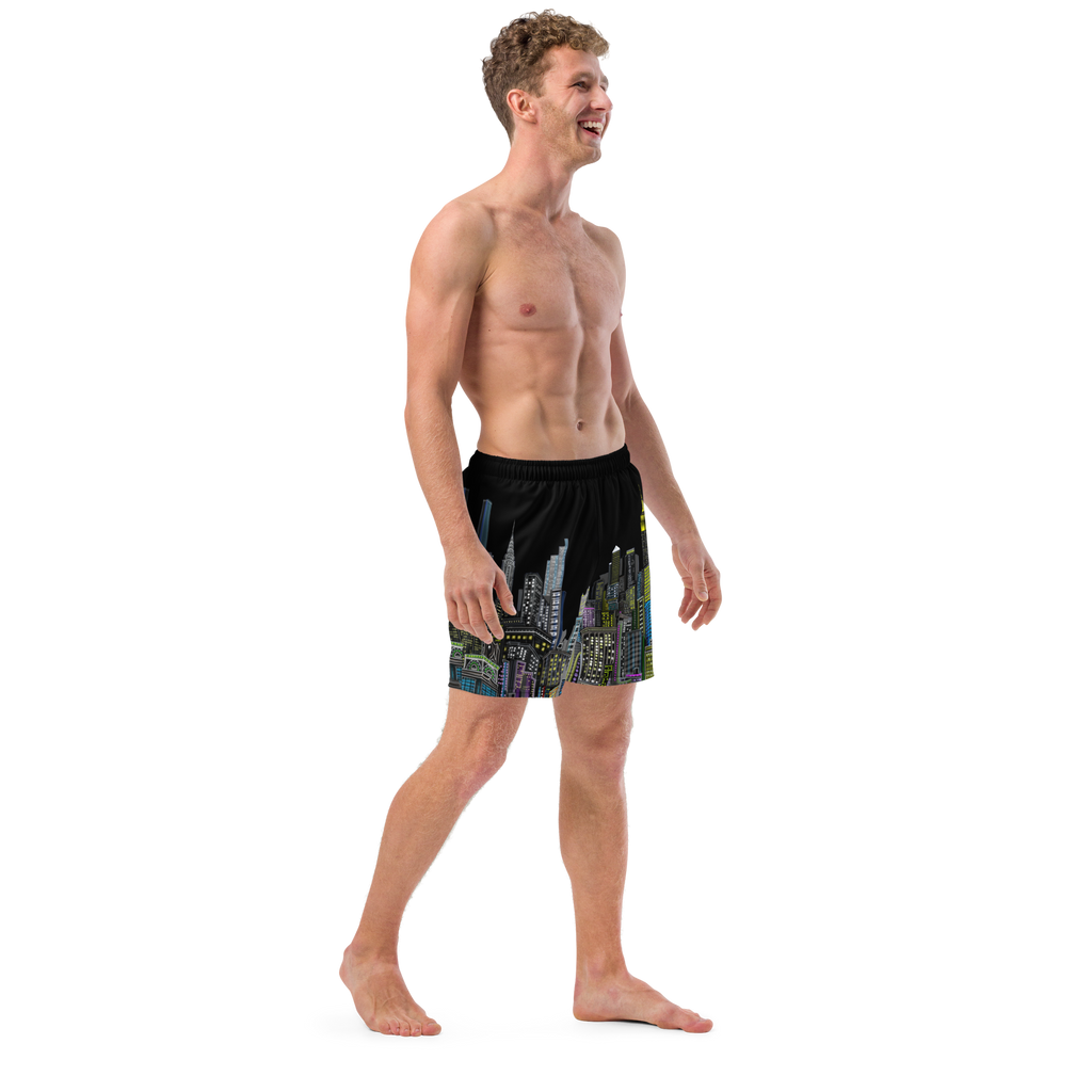 Man wearing black swim Loria NYC Art shorts with a colorful cityscape design on a white background