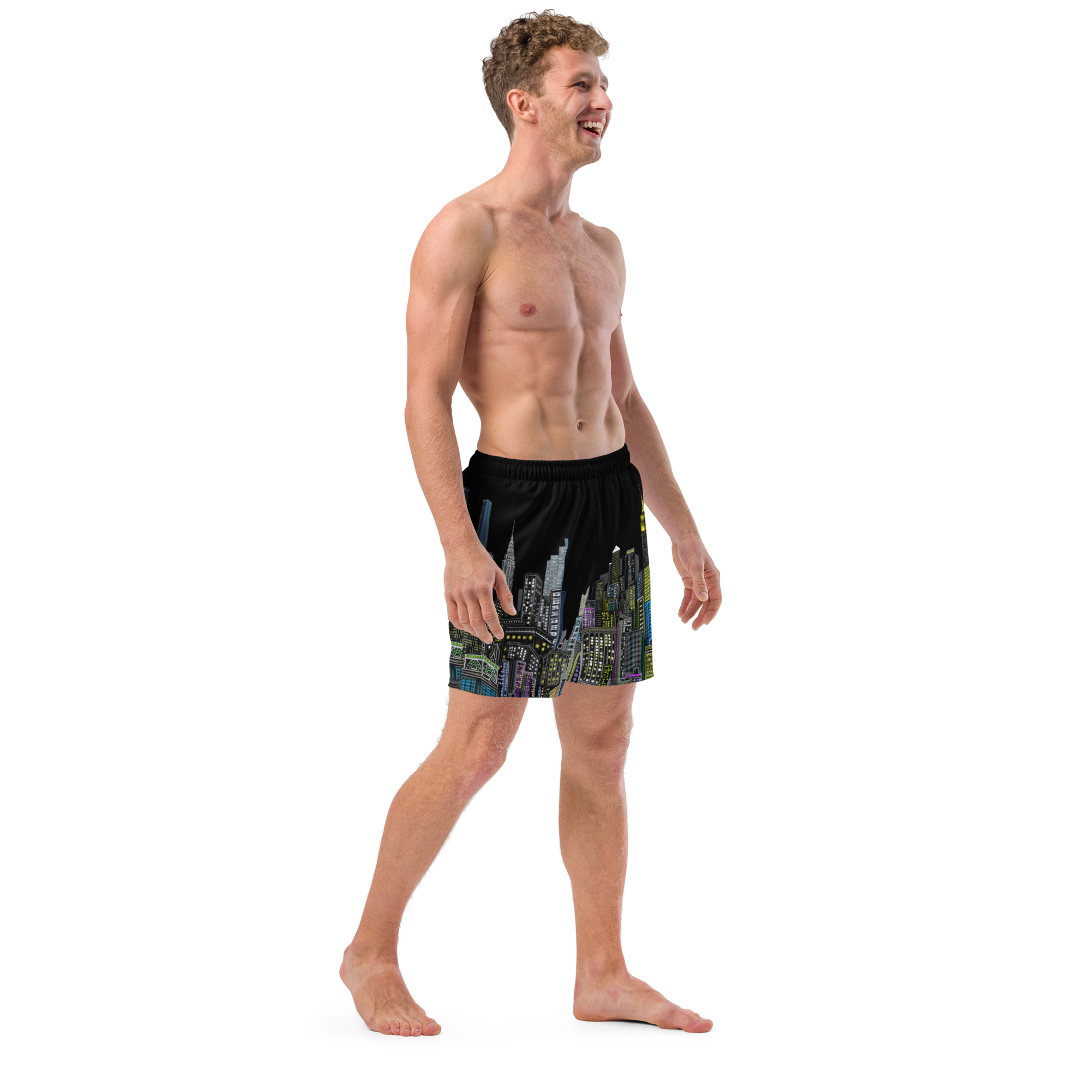 Man wearing black swim Loria NYC Art shorts with a colorful cityscape design on a white background