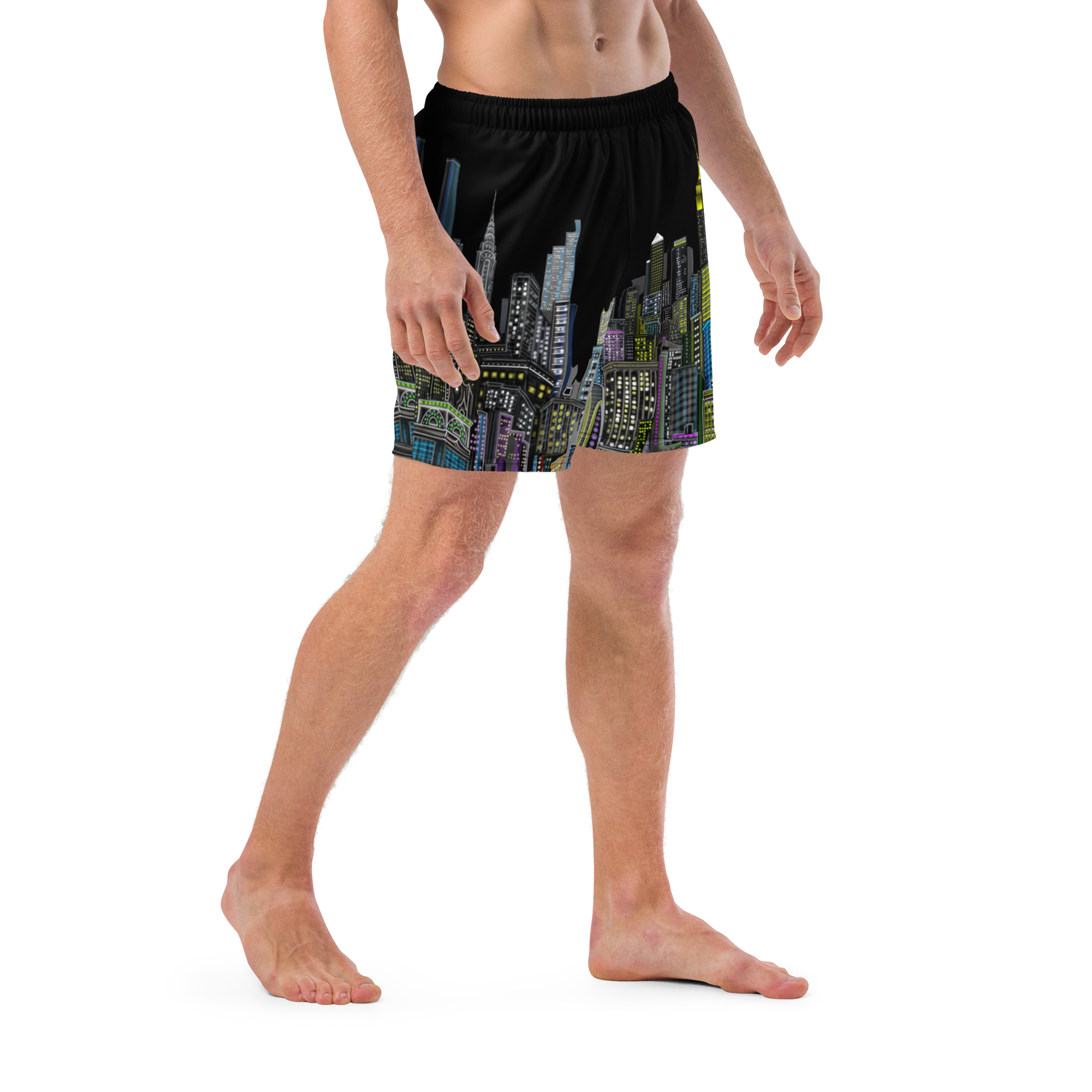 Person wearing black Loria NYC Art swim shorts with colorful cityscape design on a white background