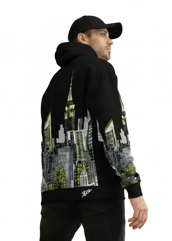Man posing and wearing a black Loria NYC Art hoodie with cityscape design, standing on white background.
