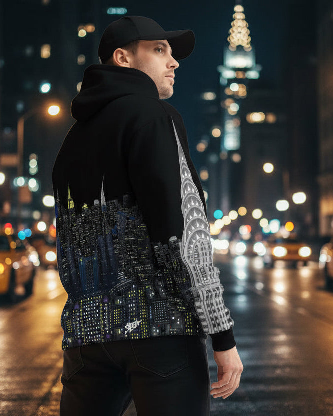 Person wearing a black hoodie with cityscape Loria NYC Art design and white cap, leaning against a wall.