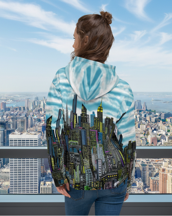 Person wearing a hoodie with a Loria NYC Art cityscape design, standing between two plants.