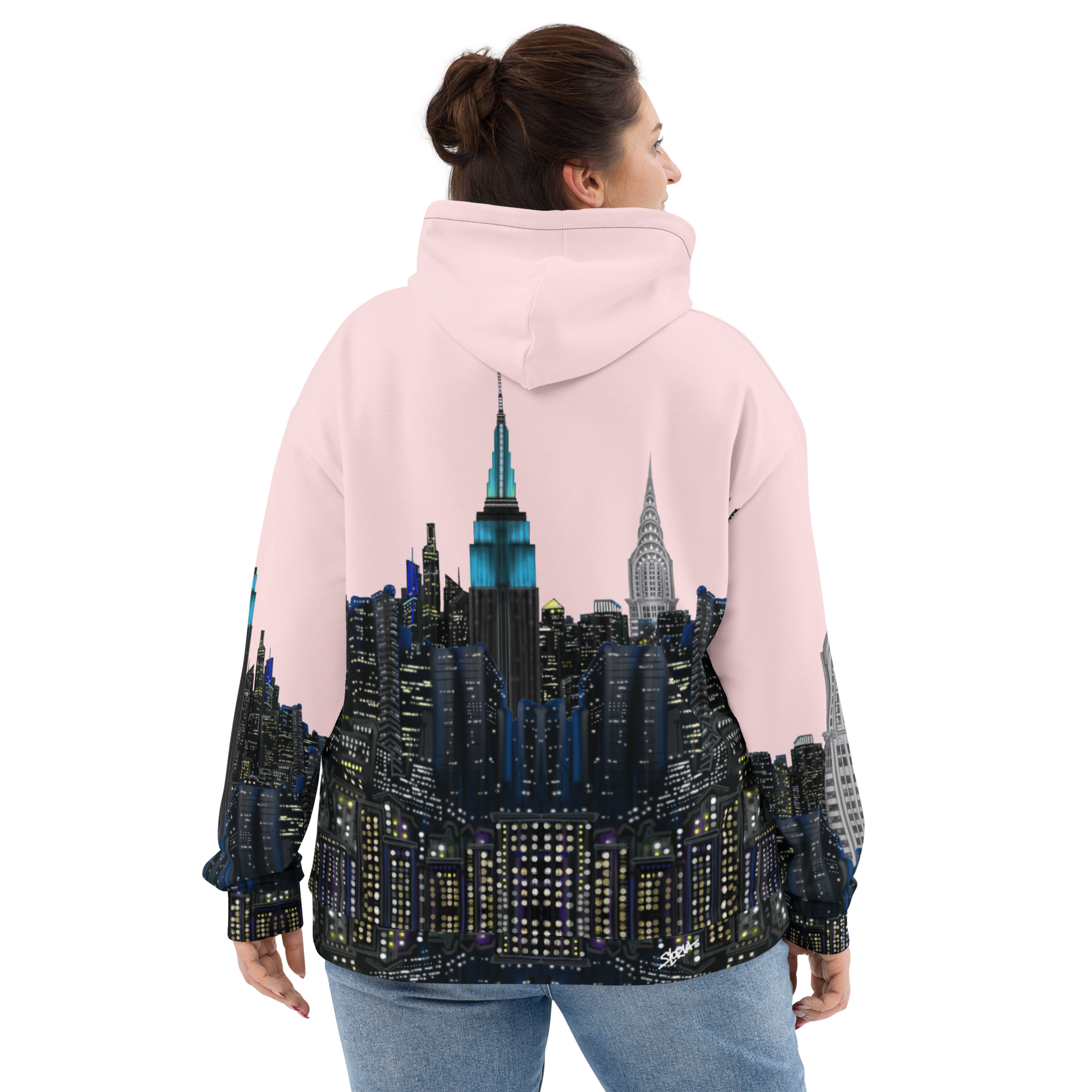 Person wearing a pink Loria NYC Art hoodie with a cityscape design on the back, standing against a white background.