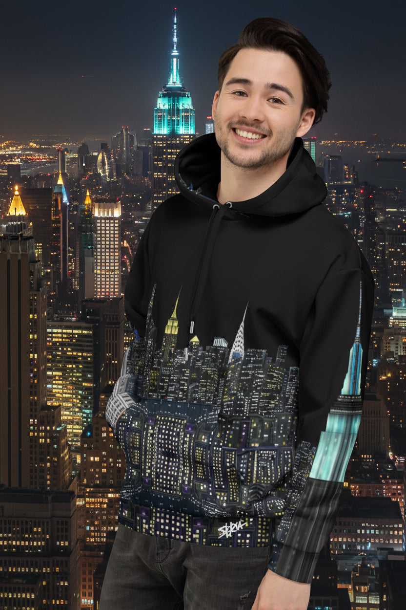 Man wearing a Loria NYC Art black hoodie with cityscape design on a skyline background