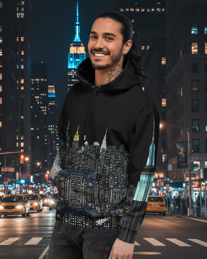 Man wearing a Loria NYC Art hoodie standing on a city street at night with illuminated buildings and traffic lights.