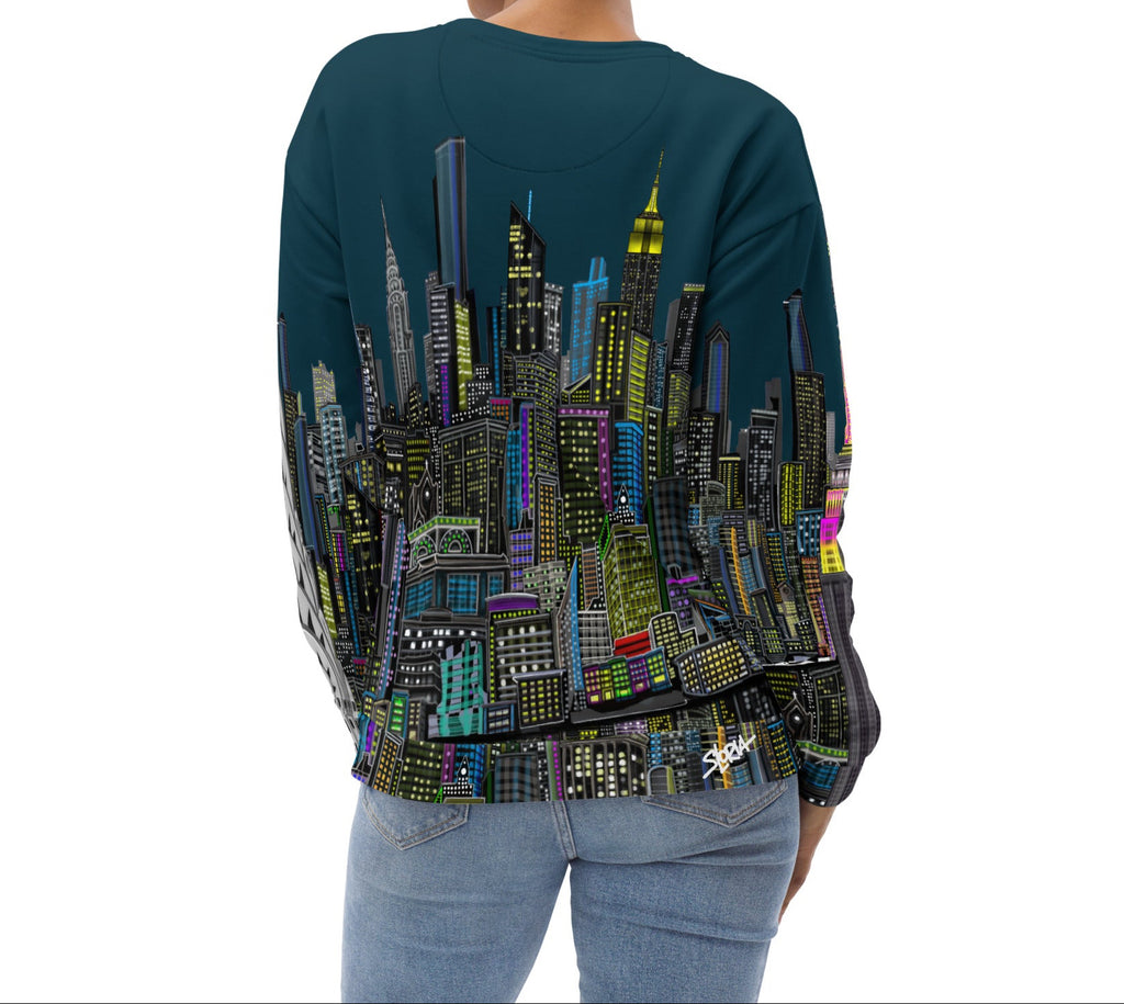 Back of Girl wearing a long-sleeve blue shirt with a cityscape design by Loria NYC Art on a white background