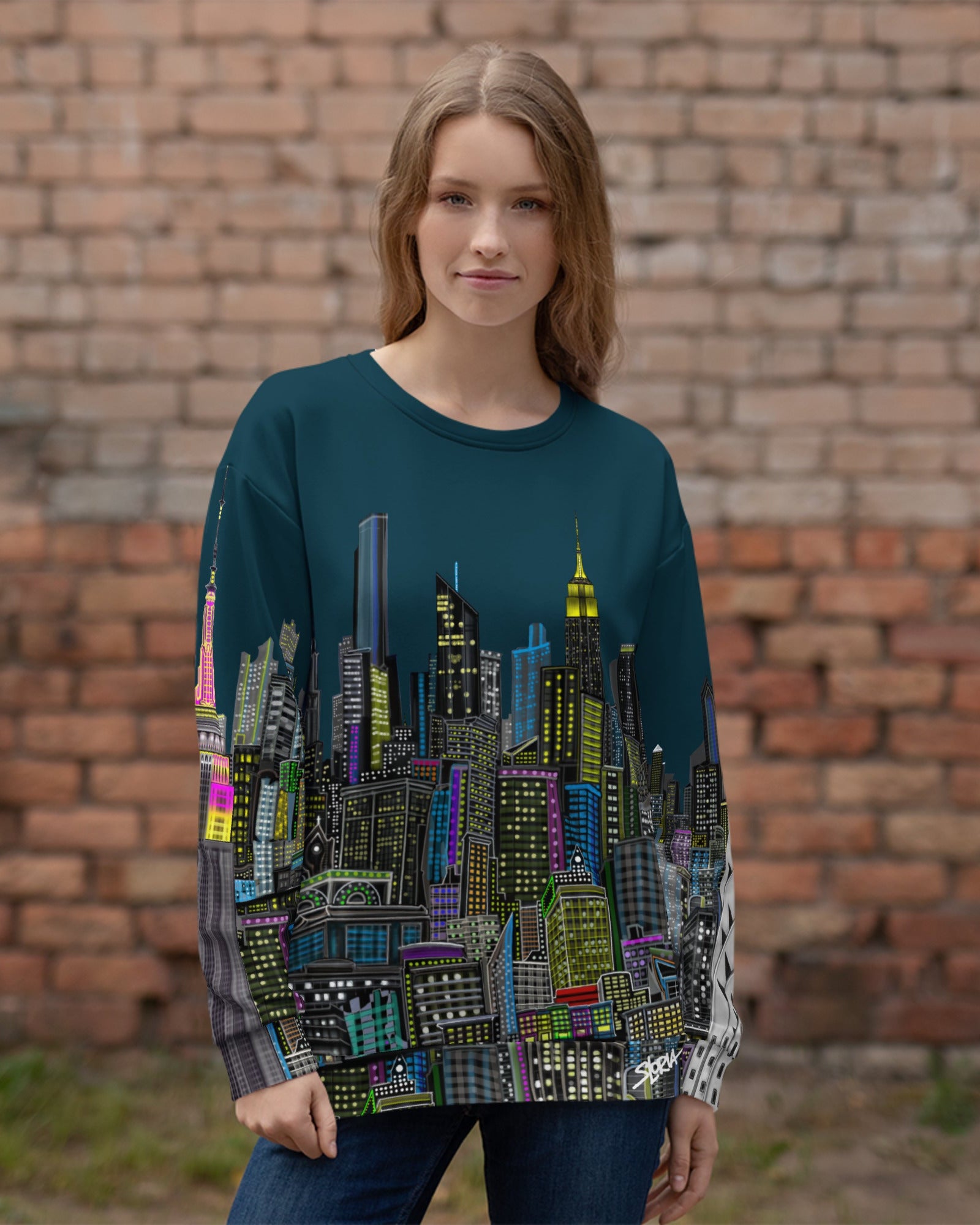 Girl wearing a long-sleeve shirt with a cityscape design by Loria NYC Art on a brick background