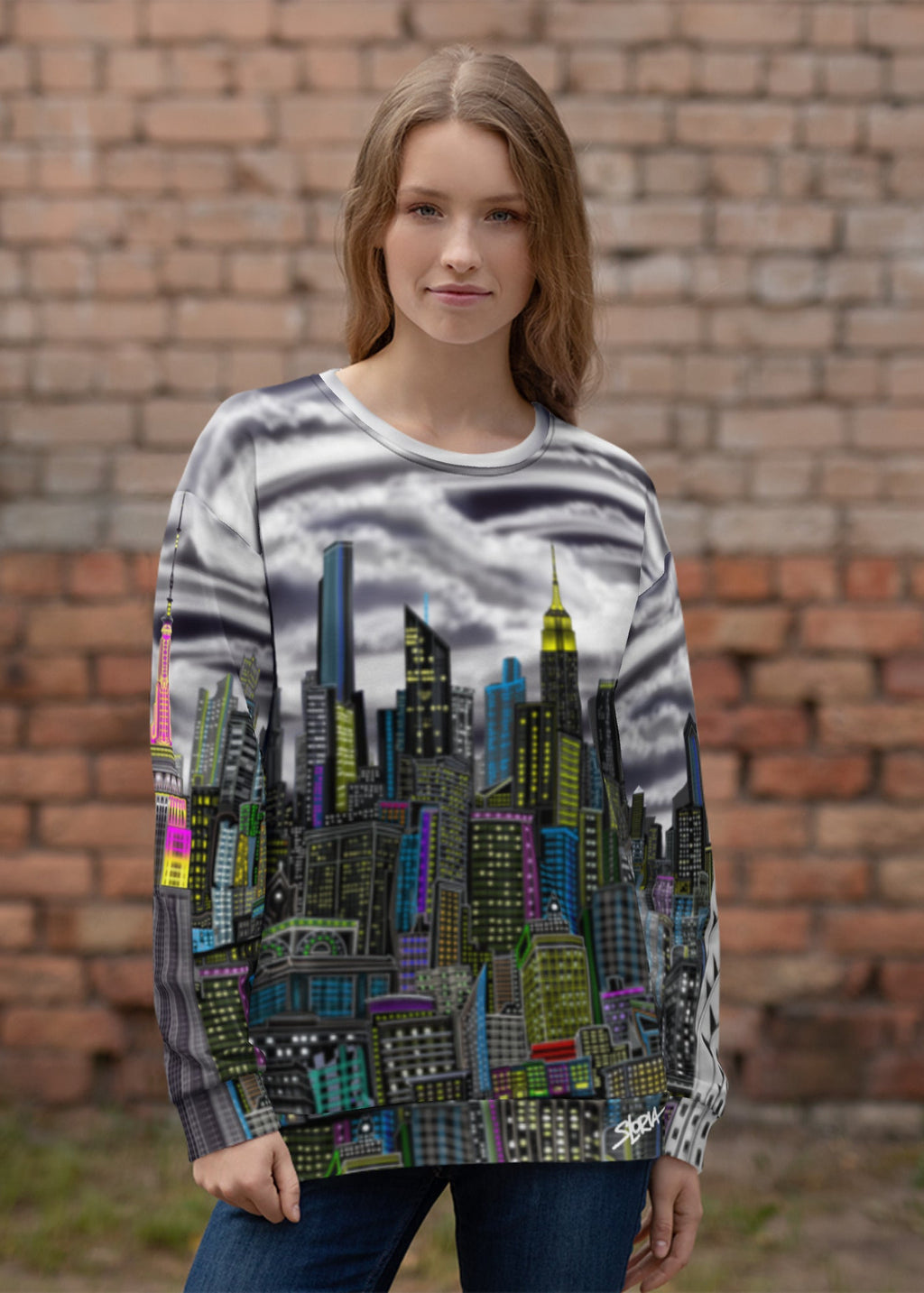 Woman wearing a Sweatshirt designed by Loria NYC Art with a cityscape design in front of a brick wall.