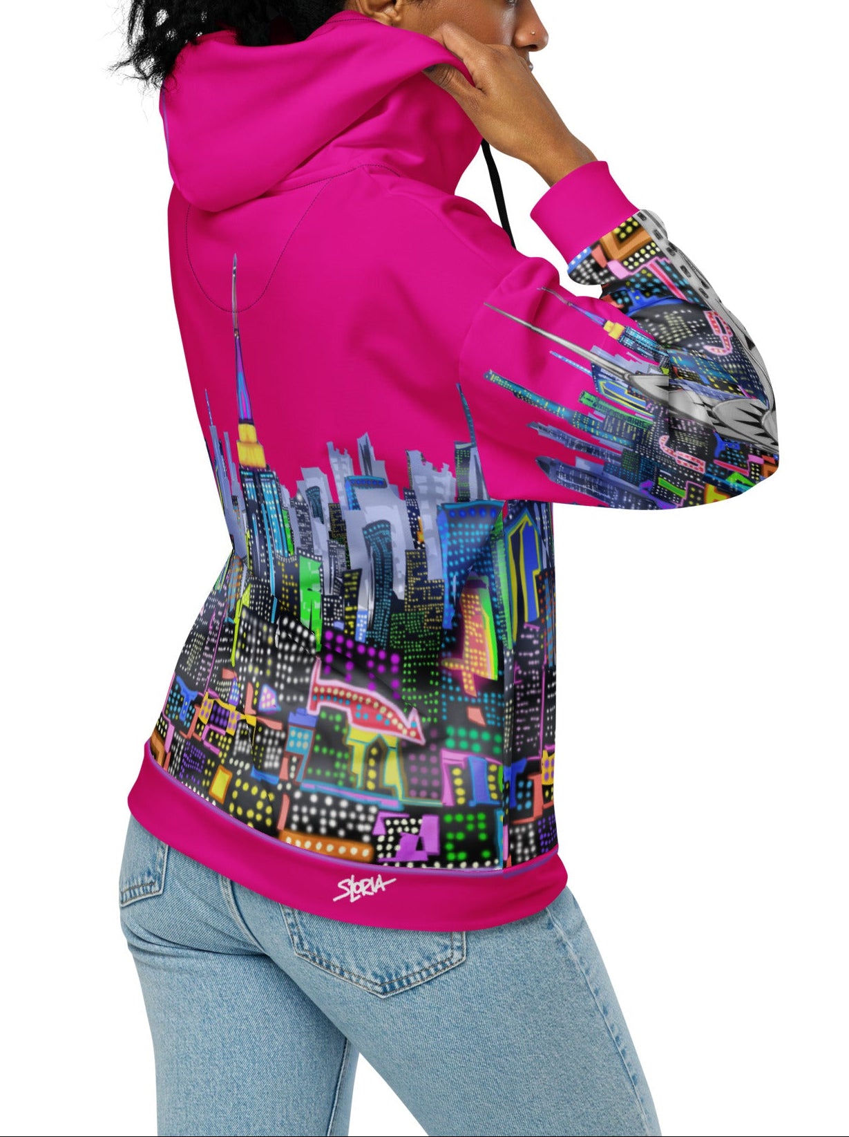 Person wearing a pink Loria NYC Art hoodie with a colorful cityscape design on the back, on a white background