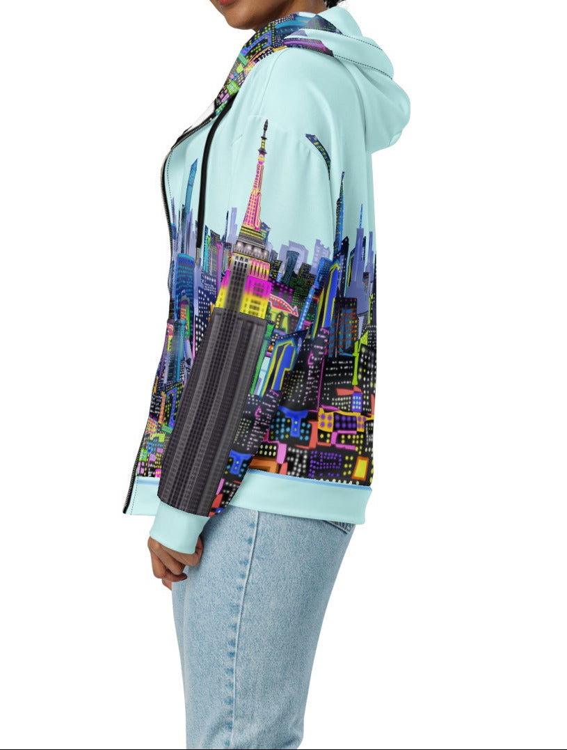 Side view of Woman wearing a Loria NYC Art hoodie with a colorful cityscape design on a white background