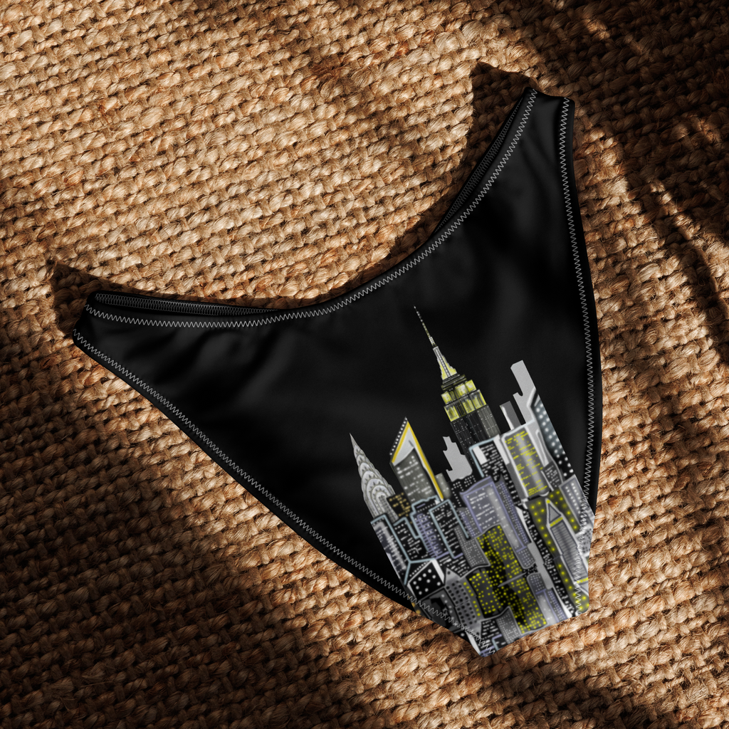 Black swim brief with cityscape Loria NYC Art design on a textured brown surface