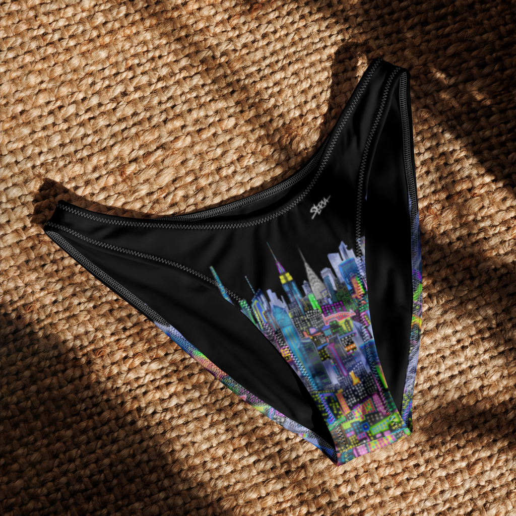 Black bikini bottom with colorful cityscape Loria NYC Art design on a textured brown surface