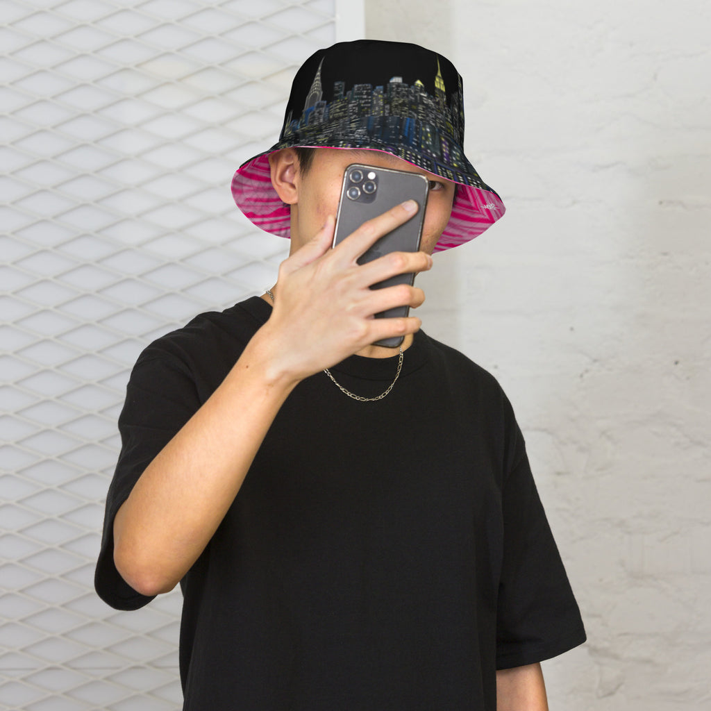 Person wearing a colorful Loria NYC Art bucket hat and black t-shirt taking a mirror selfie.